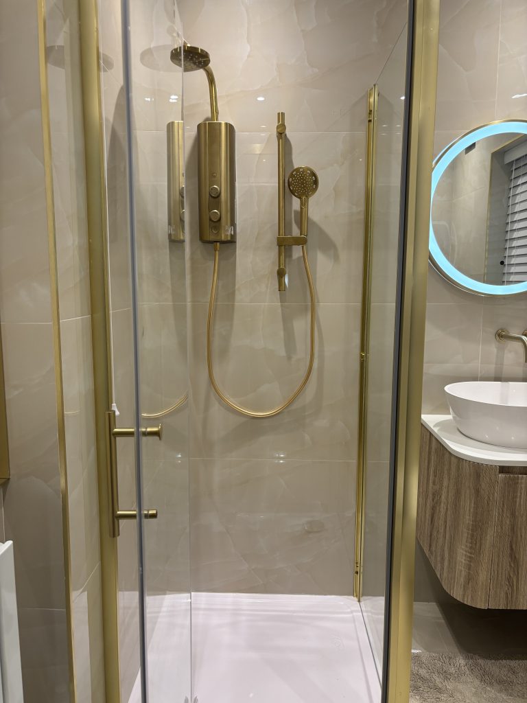 Cream marble tiled shower with gold electric shower unit, fitted by Premier Gas Burnley